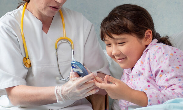 Asian girl at hospital getting her blood sugar measured by doctor or nurse during medical health check-up to prevent diabetes - Powered by Adobe