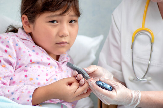 Asian girl at hospital getting her blood sugar measured by doctor or nurse during medical health check-up to prevent diabetes