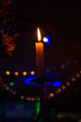 VELA ENCENDIDA EN LA OSCURIDAD CON LUCES DE FONDO
