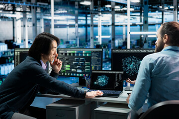 Software developers in data center troubleshooting server connectivity issues using AI. Asian man...