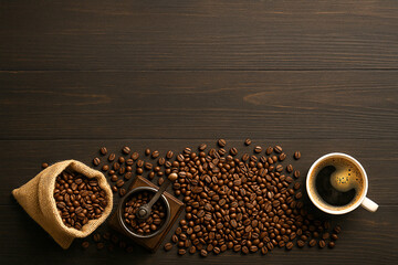 Freshly brewed coffee in white cup with grinder and coffee beans on wood background