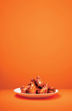 Hot Wings on White Plate and Orange Background With Copy Space
