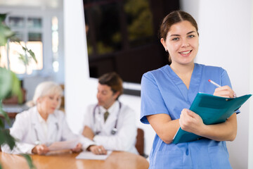 Fototapeta premium Portrait of female doctor standing in office and friendly smiling, meeting patients