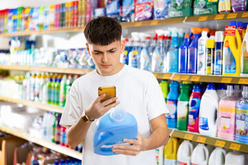 in supermarket, man carefully chooses dish detergent. buyer man scans qr code from label