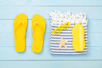 Beach towel with summer accessories on wooden background, top view