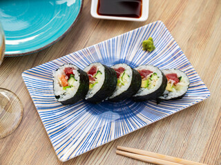 Traditional Japanese futomaki sushi with salmon, tuna, avocado, surimi and cucumber