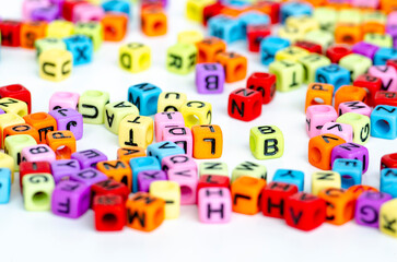 A wide spread of small colorful transparent cubes with printed letters forming a random mix scattered across a bright background symbolizing creativity and learning