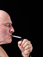 Middle aged man lighting up a cigarette,contemplating his first smoke of the day,England,United...