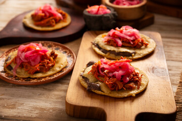Panuchos, a typical dish from Yucatan, Mexico. A handmade, fried corn tortilla filled with beans, topped with cochinita pibil, pickled red onion, and habanero pepper.