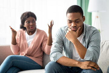 African american young couple having quarrel at home, angry black lady gesturing and shouting at...
