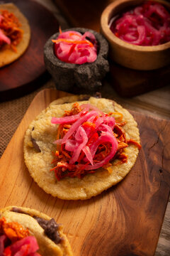 Panuchos, a typical dish from Yucatan, Mexico. A handmade, fried corn tortilla filled with beans, topped with cochinita pibil, pickled red onion, and habanero pepper.