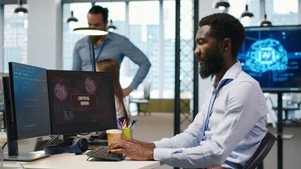 Programmer in office requesting help from coworkers to fix critical error warning. IT employee and...