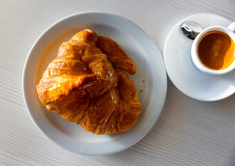 Fresh tasty croissants on table and cup of coffee in cafe
