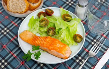 Delicious meal of seared salmon with lettuce and tomatoes salad