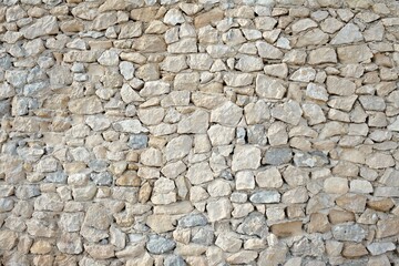 Masonry wall of natural brown stones with irregular pattern texture background