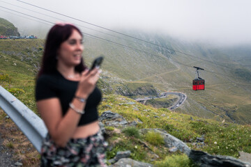 Tourist using smartphone while enjoying mountain cable car view