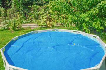 The frame pool is covered with a heat-retaining blue awning in the garden.