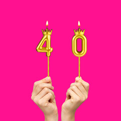 Birthday on a fuchsia background with the number 40 - Hands holding number-shaped candles