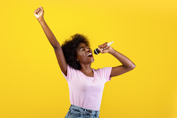 Music lover. Excited black woman singing songs in microphone and dancing, having fun and enjoying...