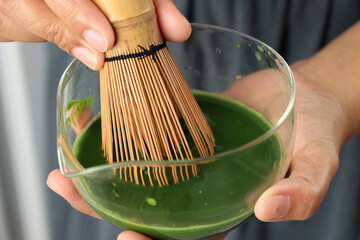 Asian Woman Hand Whiskin Mathca using Chasen on Clear Bowl