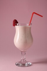 Tasty raspberry milkshake in glass on pink background