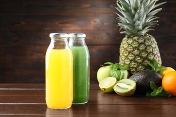 Tasty juices in glass bottles, fresh fruits, avocado and mint on wooden table, selective focus