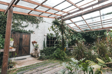 Fototapeta premium A cozy outdoor cafe surrounded by lush green garden, wooden pergola walkway, rustic architecture, natural ambiance, peaceful seating area and relaxing vibe perfect for nature lovers