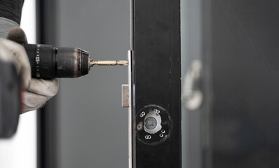 man with screw gun repairing door lock indoors