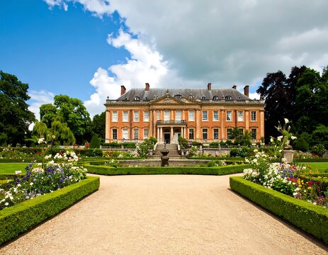 Grand estate with manicured gardens under a partly cloudy sky