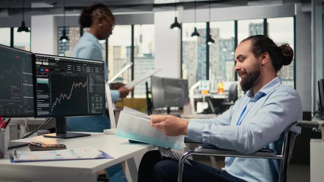 Portfolio manager in wheelchair looks over documentation files to evaluate capital allocation. Prop firm expert with disability reading paperwork documents, researching, camera A