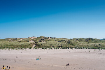 Expansive sandy beach in Donegal, Ireland, with families enjoying the sun and serene dunes in the background
