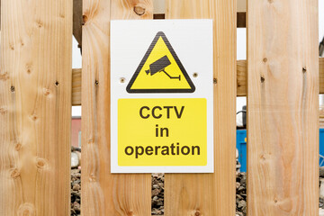 CCTV security system in operation alert sign on wooden fence for enhanced surveillance and safety...