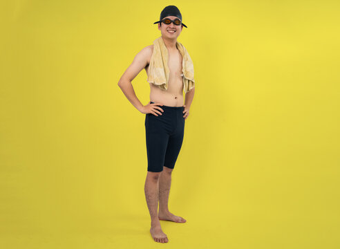 confident swimmer holding towel against yellow background in studio