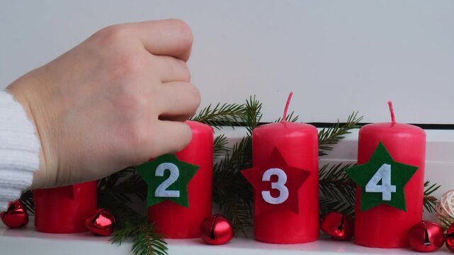 Traditional four advent weeks before Christmas holidays. Red candles with numbers burning and plastic free decoration fir brunches in windowsill. Winter cozy home time