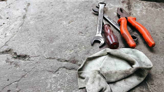 Assorted hand tools scattered across a rough cement floor with ample copy space. Ideal for construction themes, repair concepts, hardware advertising, or industrial backgrounds.