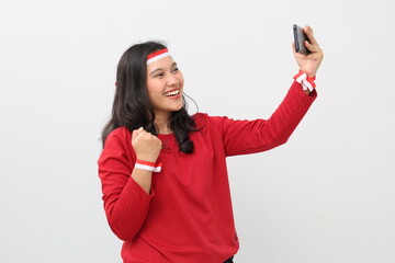Indonesian woman with red and white ribbon celebrating Indonesian Independence Day, standing...