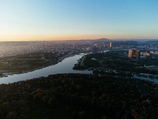 Aerial sunrise view over Belgrade city, river bend and urban skyline at golden light. g.