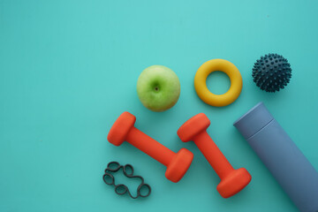 Colorful fitness tools and healthy snacks on teal background