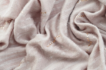Soft pink fabric draped with delicate embellishments