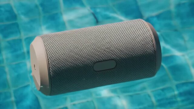 Portable Gray Speaker Floating on a Turquoise Swimming Pool Surface Creating Ripples in the Water Close Up Still Captures the Essence of Summer Leisure and Relaxation in a Contemporary Style Perfect