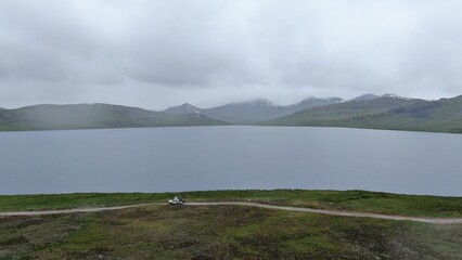 Mountain lake with green meadow and cloudy sky  Deosai lake
