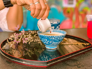 A hand is pouring rich, sweet sauce over a delicious Japanese dessert. The glossy sauce slowly drizzles and coats the surface of the treat, adding a fragrant sweetness and an irresistible glossy finis