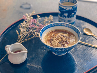 A hand is pouring rich, sweet sauce over a delicious Japanese dessert. The glossy sauce slowly drizzles and coats the surface of the treat, adding a fragrant sweetness and an irresistible glossy finis
