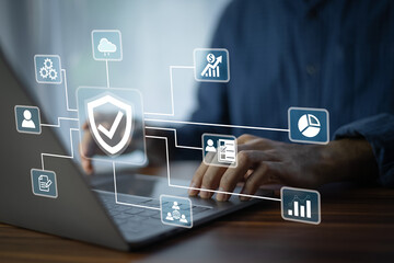 A business analyst working on a laptop monitors network security dashboards to detect risks in real...