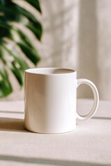 Close-up of a plain white ceramic mug with a curved handle placed on a light-colored in a well-lit indoor setting with blurred green foliage in the background