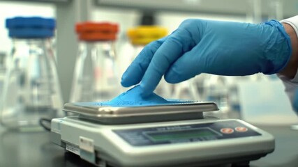 A scientist in blue protective gloves carefully measures a small amount of blue chemical powder on a high-precision digital laboratory scale for an experiment. - Powered by Adobe