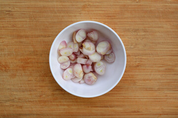 Chopped onion cloves in white bowl against wooden background, preparation process of onion for...