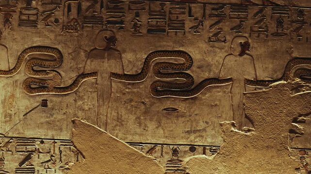 Close-up of a hieroglyphic scene in the Tomb of the Kings, showing figures holding a long snake surrounded by ancient symbols. Historic Egyptian art with religious, cultural, and mythological meaning.