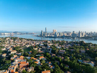Xiamen China's vibrant coastal city shows modern skyscrapers and traditional homes spread across green islands and clear blue water, presenting an expansive urban panorama.