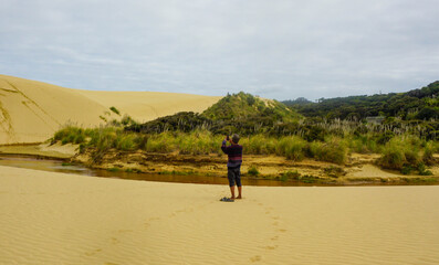 A woman walking on the Giant Sand Dunes, Cape Reinga, New Zealand.